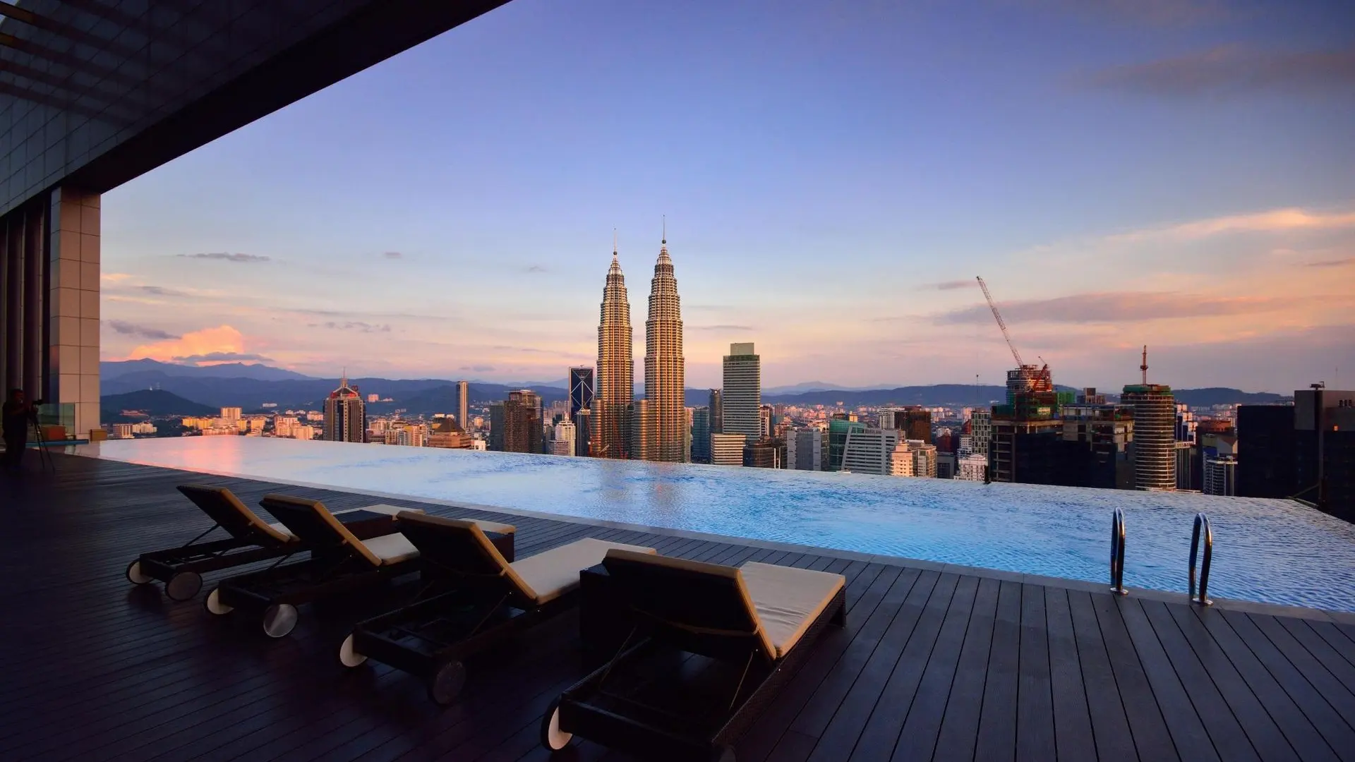 Infinity pool overlooking the Petronas Twin Towers and Kuala Lumpur skyline at dusk